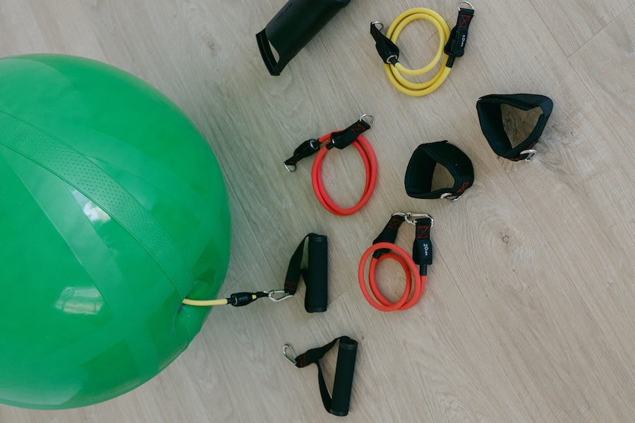 Green exercise ball with resistance bands and handles on a wooden floor