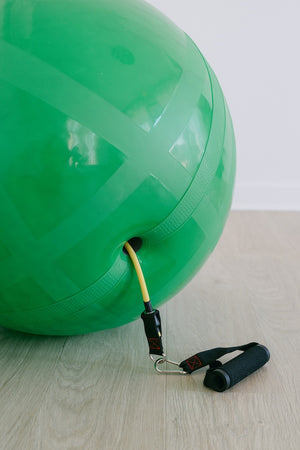 Green channel ball with resistance band on a light wooden floor