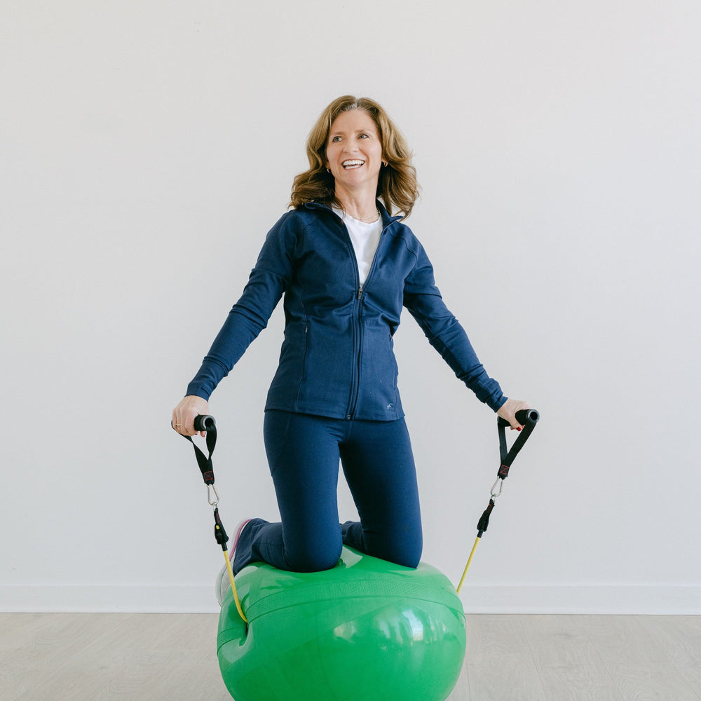 Woman using a green exercise ball with handles on a light background