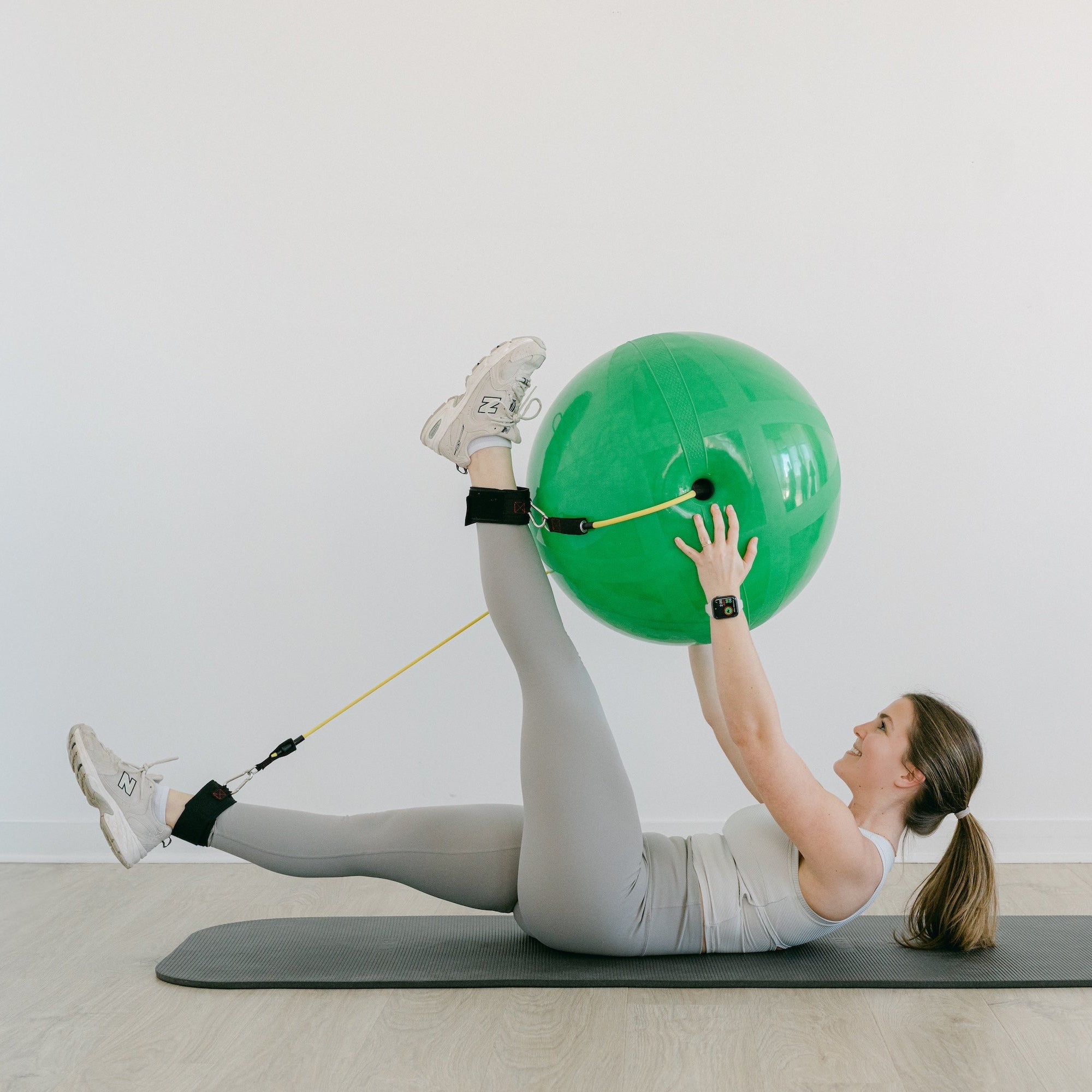 Person exercising with a green exercise ball and resistance band on a white background